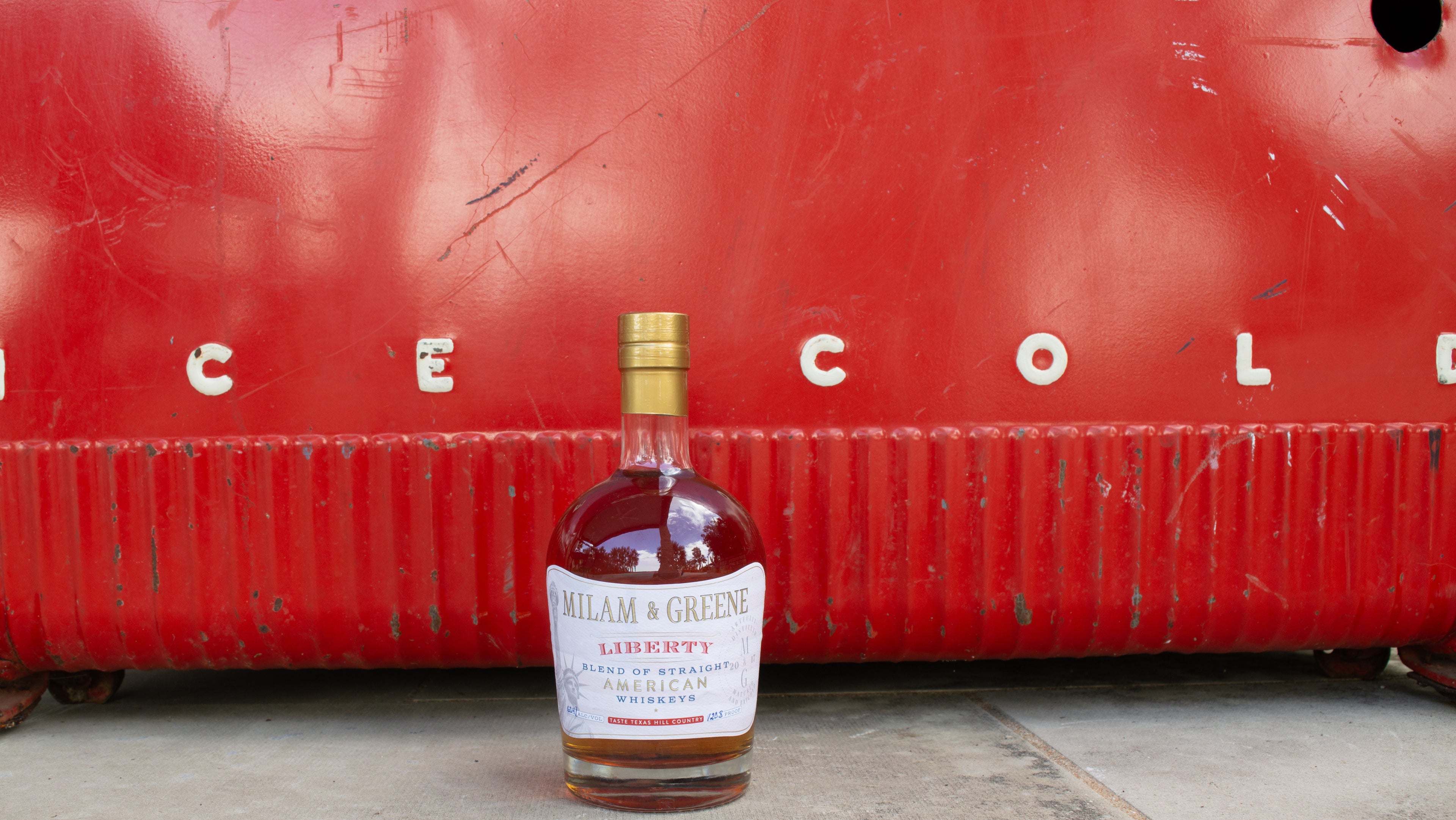 Bottle of William & George whiskey in front of a red container with 'ICE COLD' branding.