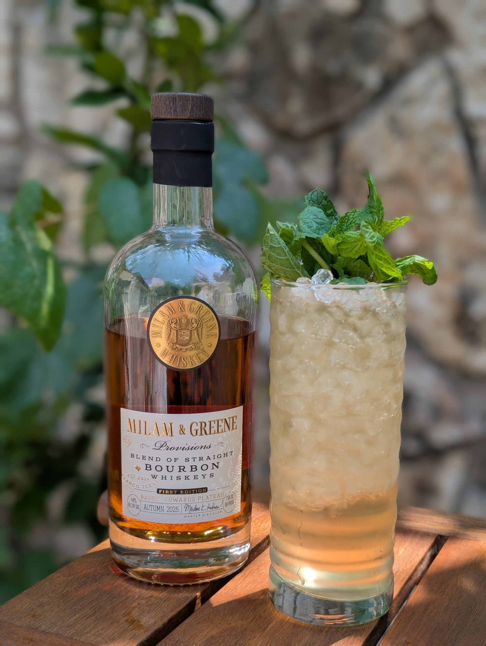 Canyon Cooler_Provisions elegant provisions bourbon bottle with the canyon cooler cocktail in a tom collins glass with mint and using coconut water and ginger beer or ginger ale